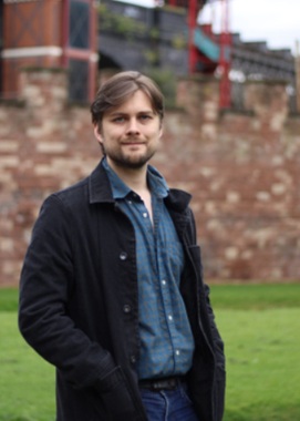 Image of author Tom Lee against a brick and grass background